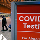 Travelers pass a sign near a COVID-19 testing site in Terminal E at Logan Airport, on Dec. 21, 2021, in Boston